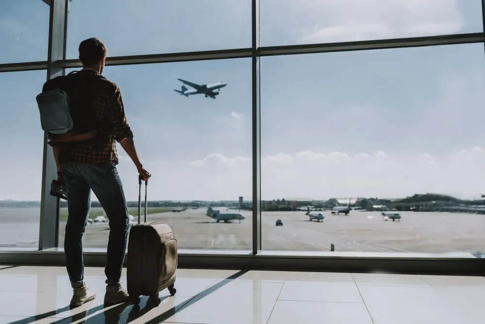 Man watching plane take off from airport window